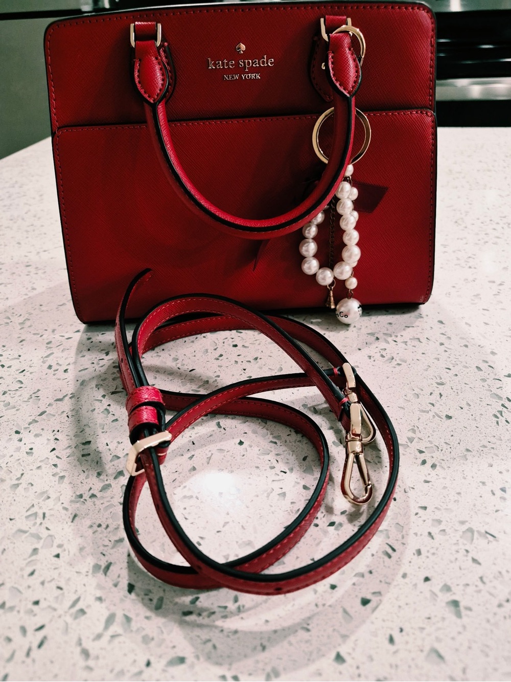 This red satchel is a Kate Spade New York Madison Saffiano Leather